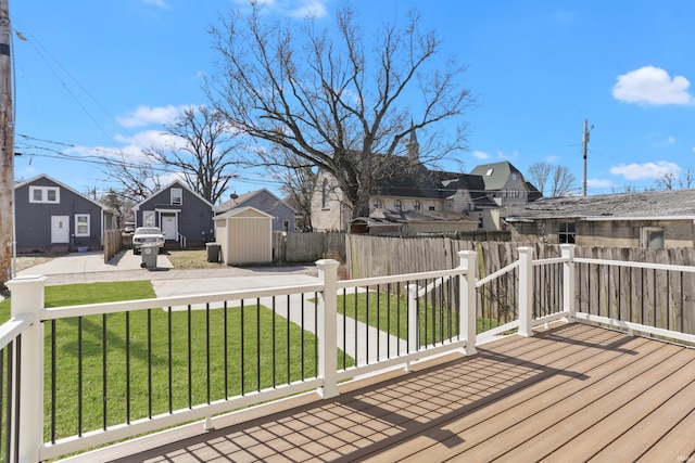 wooden deck with an outbuilding, a storage unit, fence private yard, a lawn, and a residential view