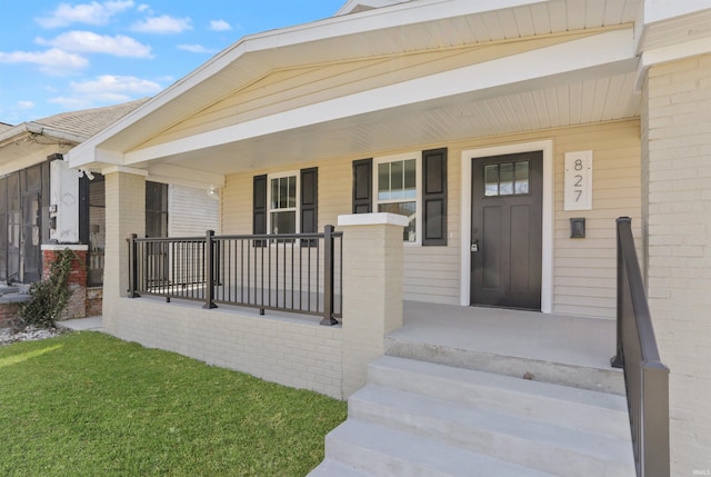 doorway to property with brick siding and covered porch