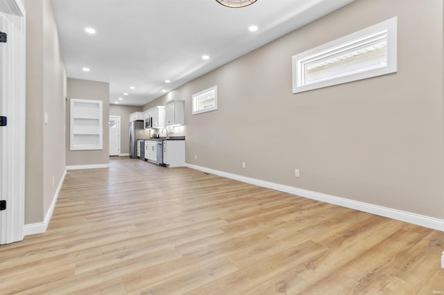 unfurnished living room with light wood-style flooring, recessed lighting, and baseboards