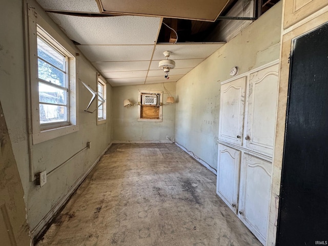 spare room with a wall mounted air conditioner, a drop ceiling, and concrete floors