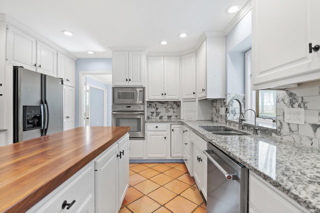 kitchen featuring a sink, stainless steel appliances, wooden counters, and white cabinetry