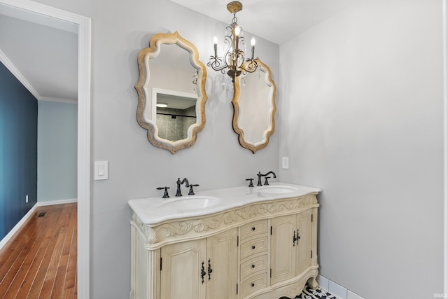 bathroom with wood finished floors, baseboards, a chandelier, and a sink