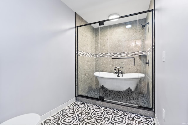 bathroom with a freestanding tub, toilet, a stall shower, tile patterned flooring, and baseboards