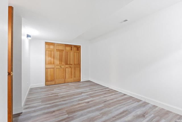 unfurnished bedroom with a closet, visible vents, baseboards, and light wood-style floors