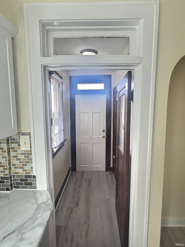 doorway featuring wood finished floors, baseboards, and arched walkways