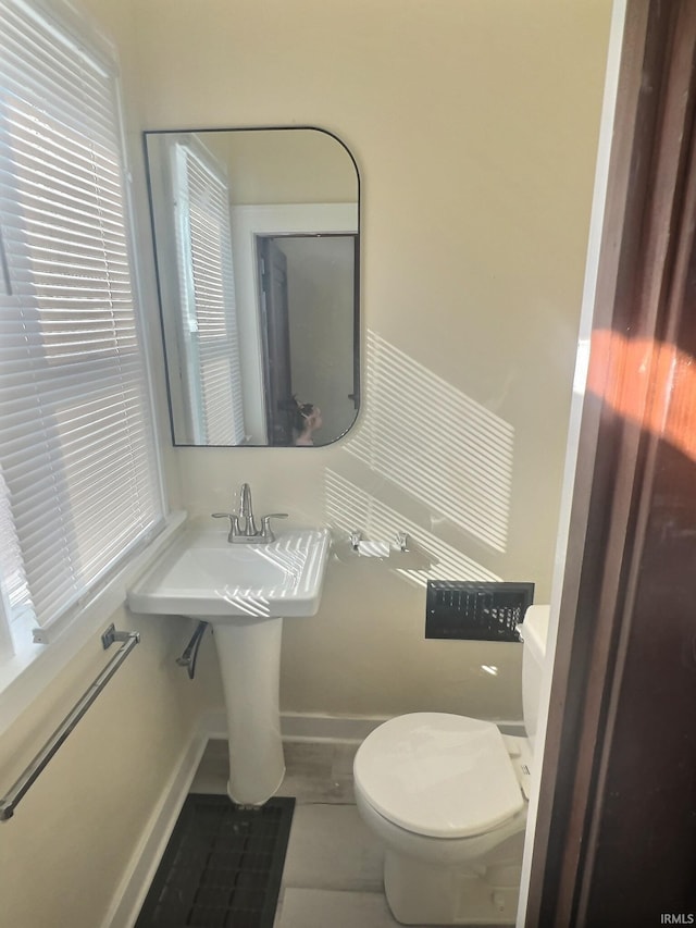 half bath with baseboards and toilet