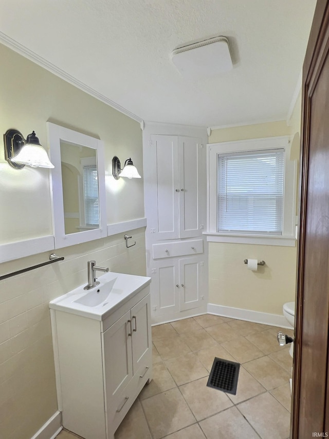 bathroom with vanity, ornamental molding, tile patterned floors, toilet, and tile walls