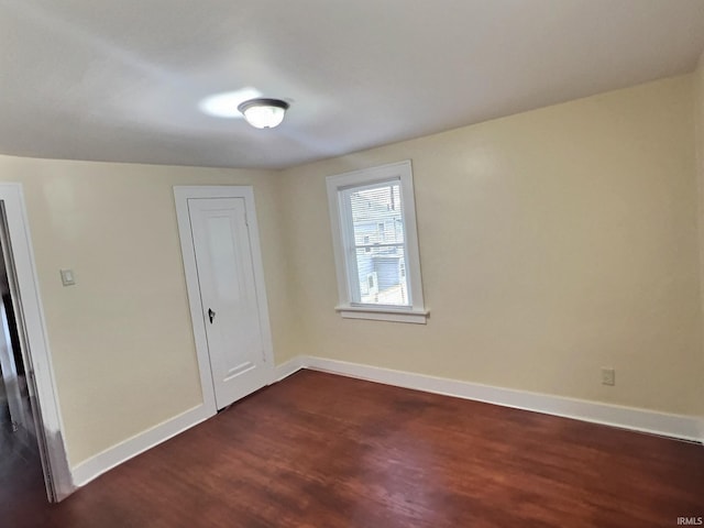 empty room with dark wood-style floors and baseboards