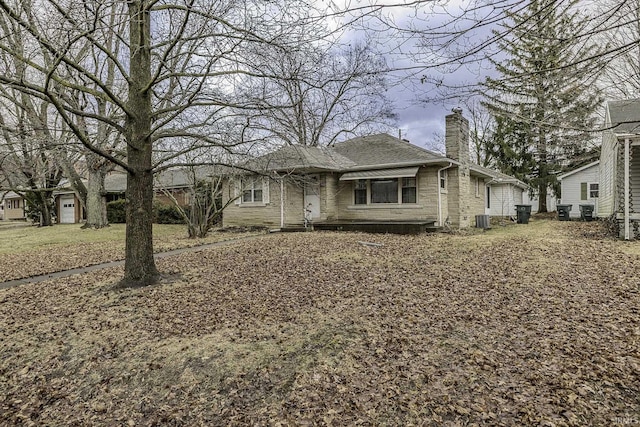 view of front of property featuring central air condition unit, a chimney, and a shingled roof