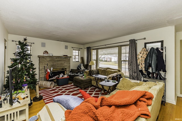 living area with a fireplace, wood finished floors, baseboards, and a textured ceiling