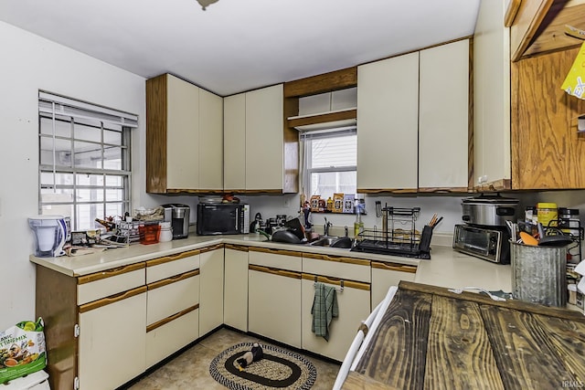 kitchen with a toaster, white cabinetry, light countertops, and a sink