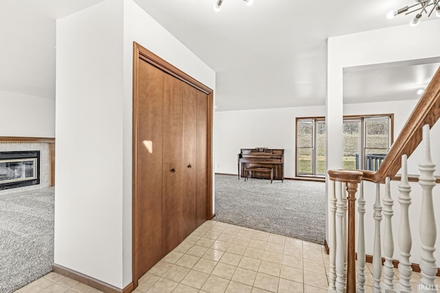 hallway with light tile patterned floors, baseboards, and light carpet