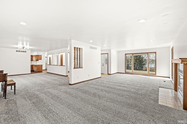 unfurnished living room with a tiled fireplace, light colored carpet, visible vents, and baseboards