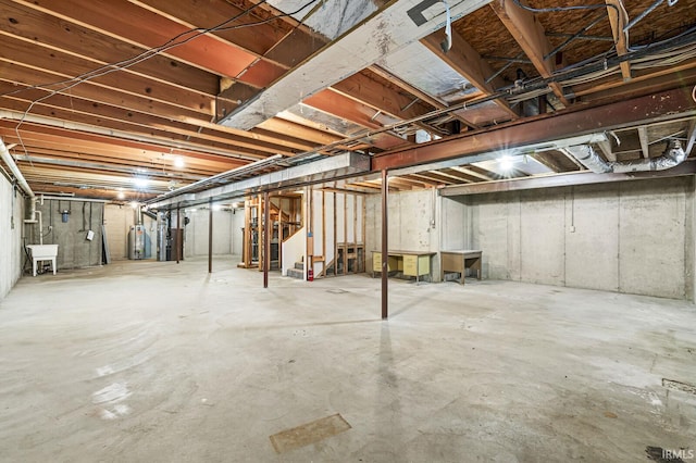 unfinished below grade area featuring water heater, stairs, and a sink