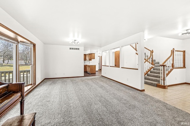 unfurnished living room with visible vents, stairway, carpet flooring, tile patterned flooring, and baseboards