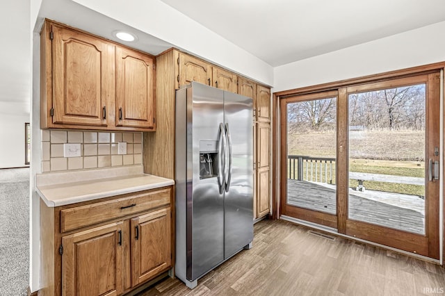 kitchen with visible vents, backsplash, light countertops, stainless steel refrigerator with ice dispenser, and wood finished floors