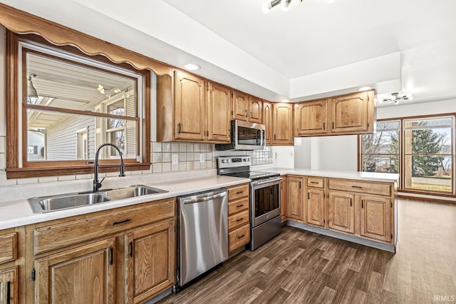 kitchen with light countertops, decorative backsplash, dark wood-style floors, stainless steel appliances, and a sink