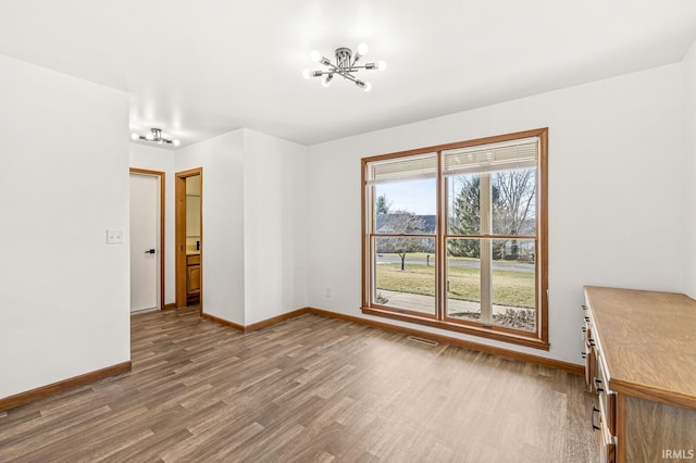 interior space with a chandelier, baseboards, and wood finished floors