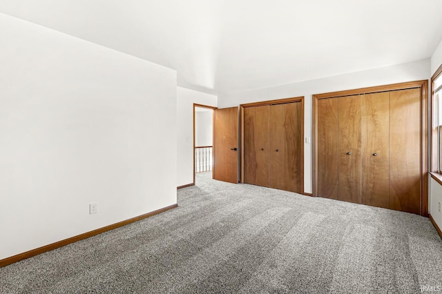 unfurnished bedroom featuring baseboards, multiple closets, and carpet floors