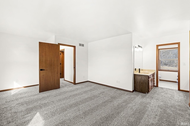 unfurnished bedroom featuring baseboards, visible vents, carpet floors, and a sink