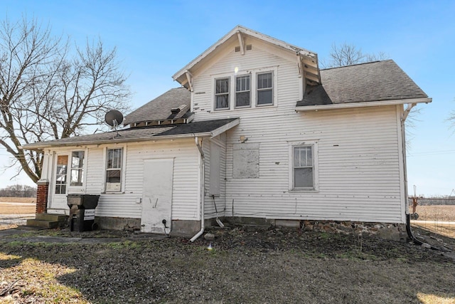 back of house featuring entry steps and roof with shingles