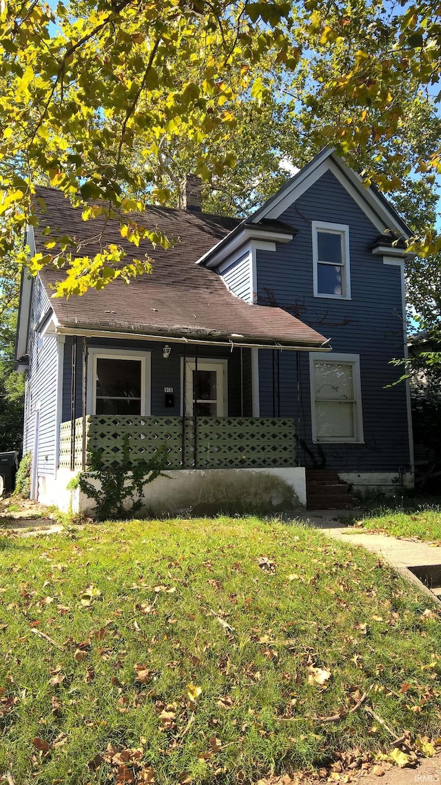 view of front facade with entry steps, a chimney, and a front yard