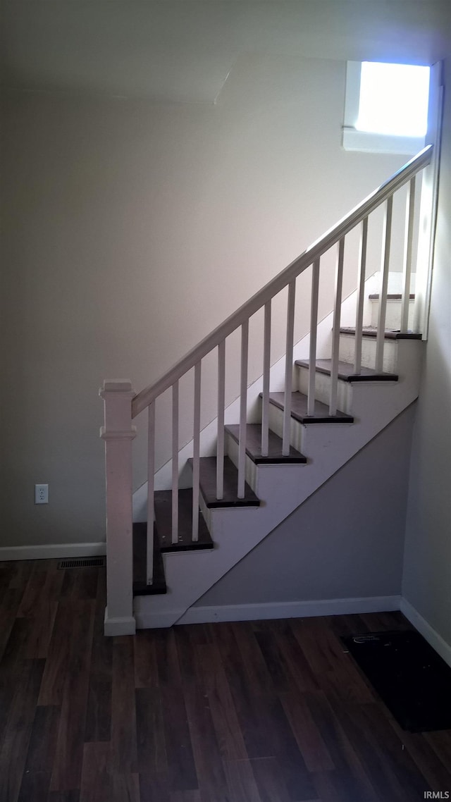 staircase with visible vents, baseboards, and wood finished floors