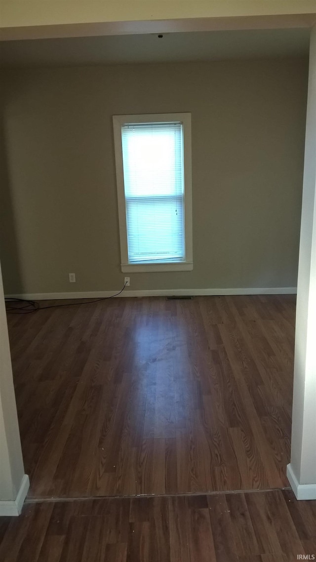 spare room with baseboards and wood finished floors