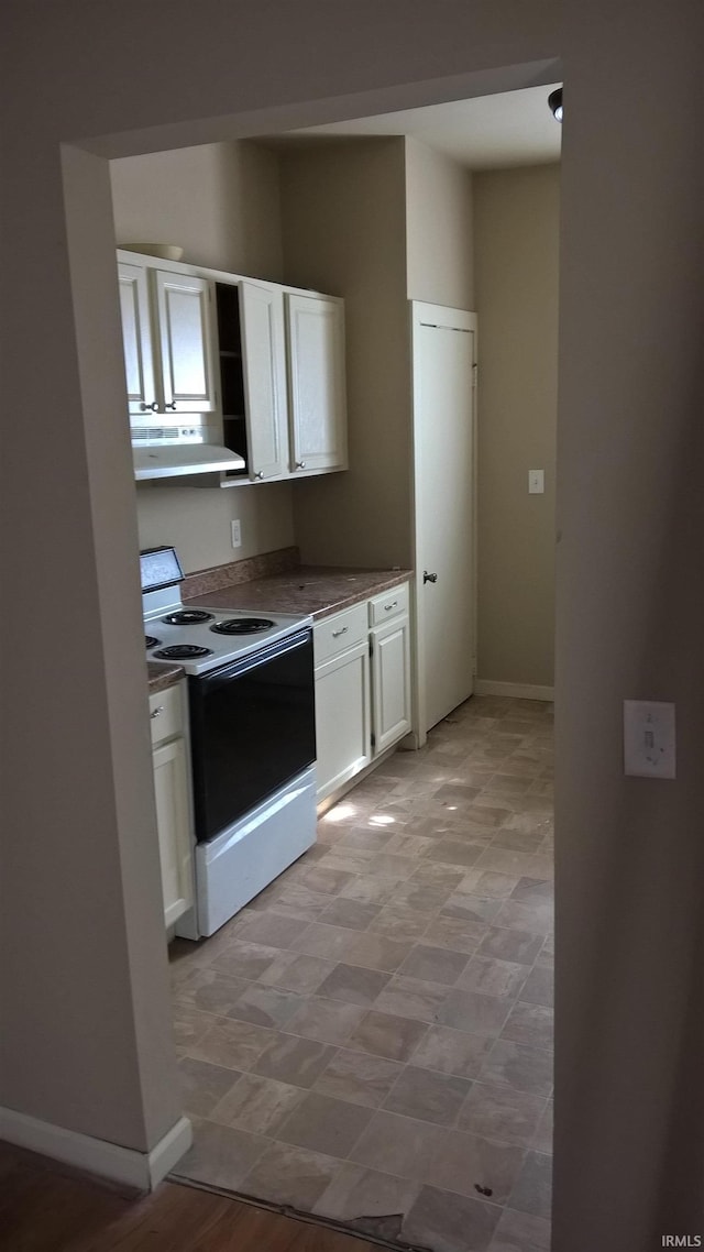 kitchen featuring under cabinet range hood, baseboards, white cabinets, and electric range oven