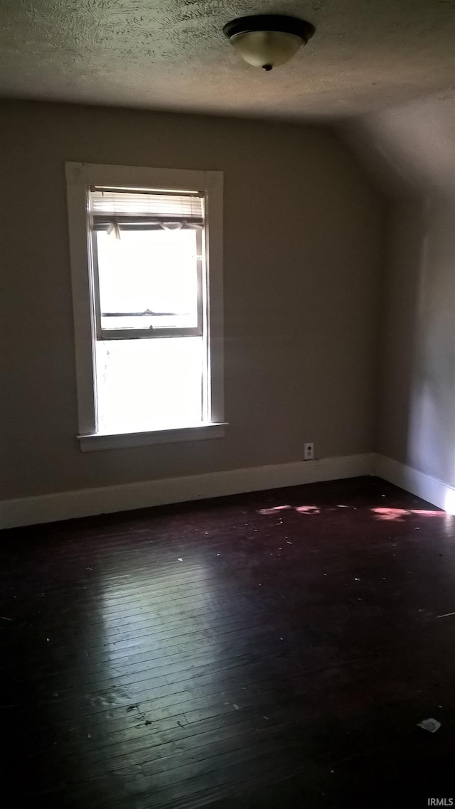 additional living space featuring dark wood-style floors, baseboards, and a textured ceiling