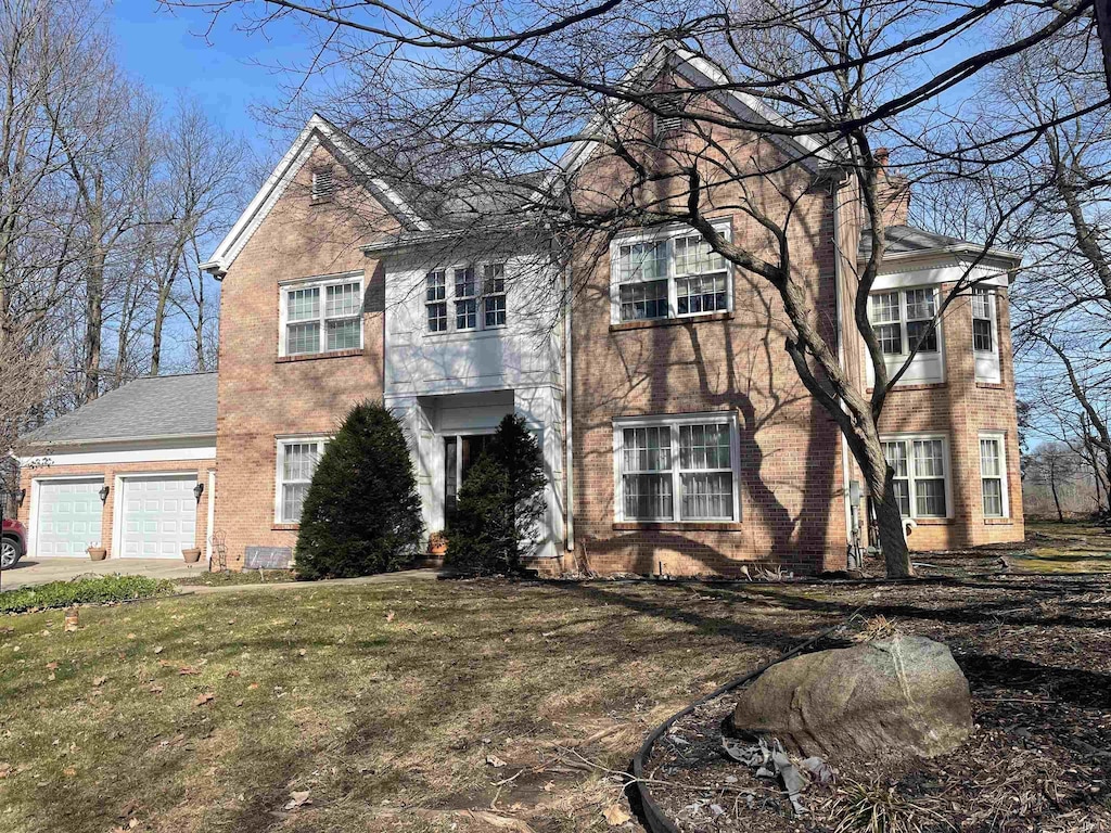 view of front of property with a front lawn, brick siding, a garage, and driveway