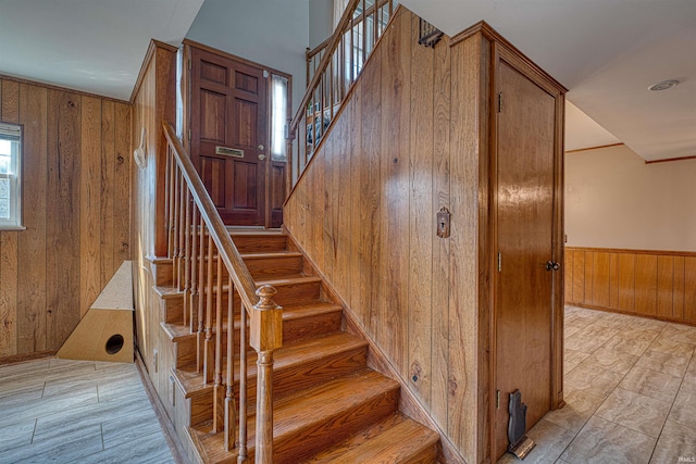 stairway featuring wooden walls and wainscoting