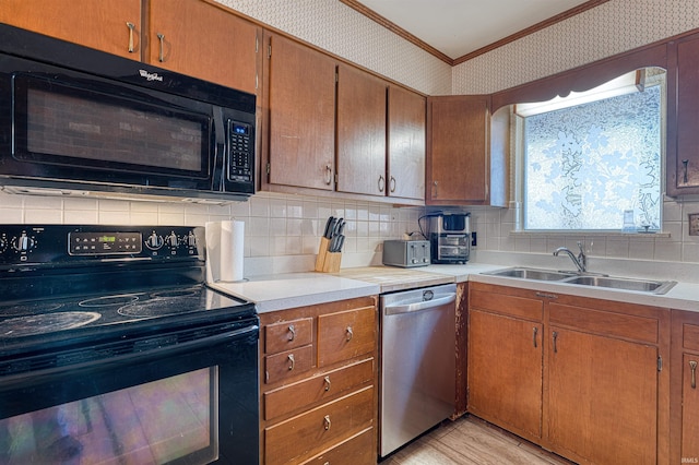 kitchen with tasteful backsplash, wallpapered walls, ornamental molding, black appliances, and a sink