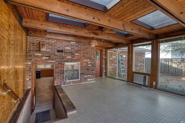 unfurnished sunroom featuring beam ceiling, a skylight, wood ceiling, and ceiling fan