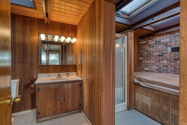 bathroom featuring vanity, brick wall, wood walls, and a shower stall