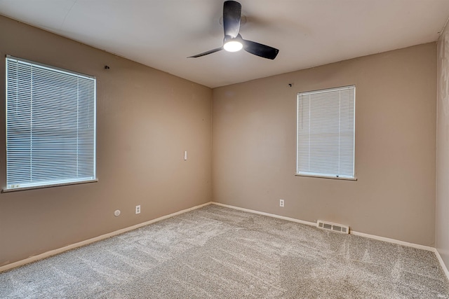 carpeted spare room with visible vents, baseboards, and ceiling fan