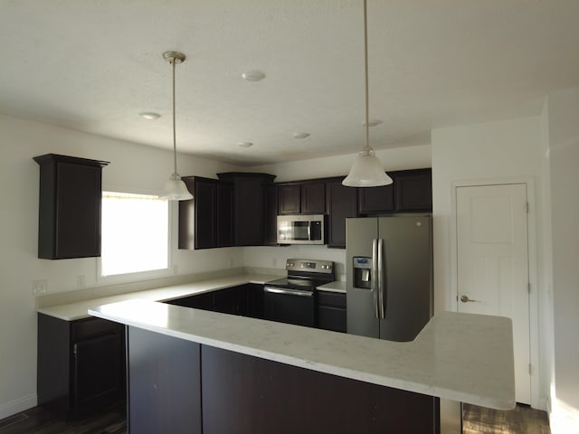 kitchen with stainless steel appliances, baseboards, dark cabinetry, and hanging light fixtures