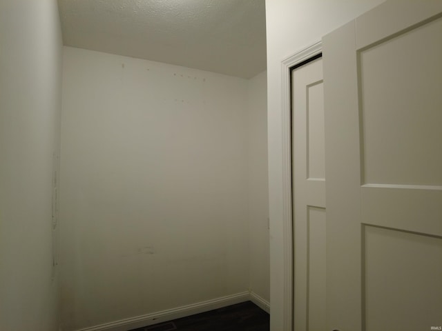 interior space with baseboards, a textured ceiling, and dark wood-style flooring