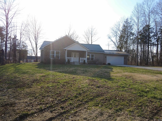 ranch-style home with a porch, a front yard, driveway, an attached garage, and a standing seam roof