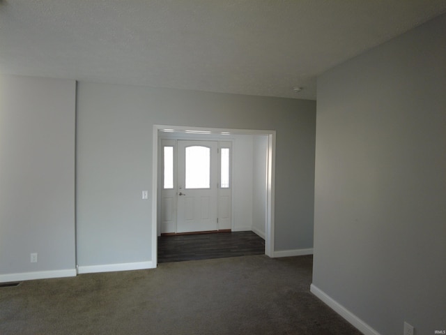 entrance foyer with dark carpet and baseboards