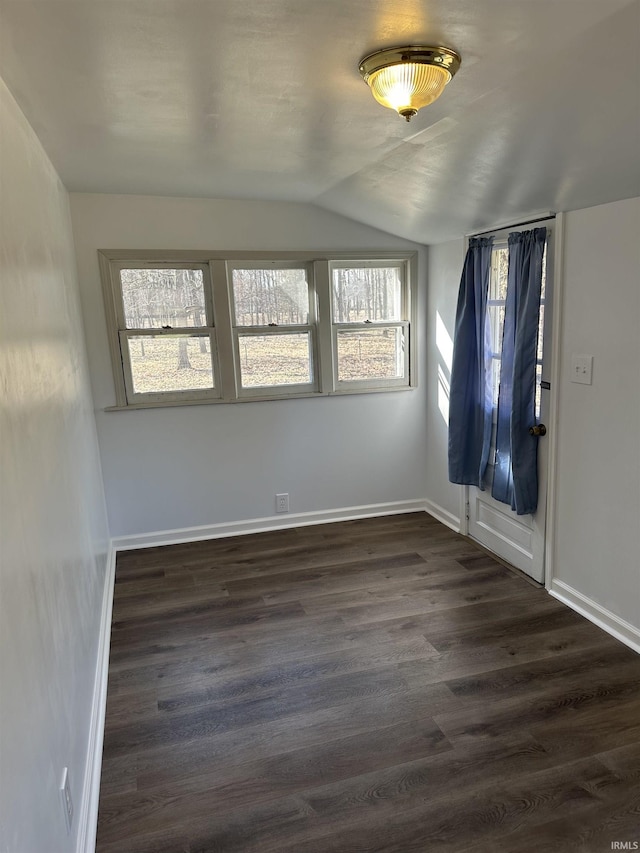 unfurnished room featuring baseboards, plenty of natural light, dark wood-style flooring, and vaulted ceiling