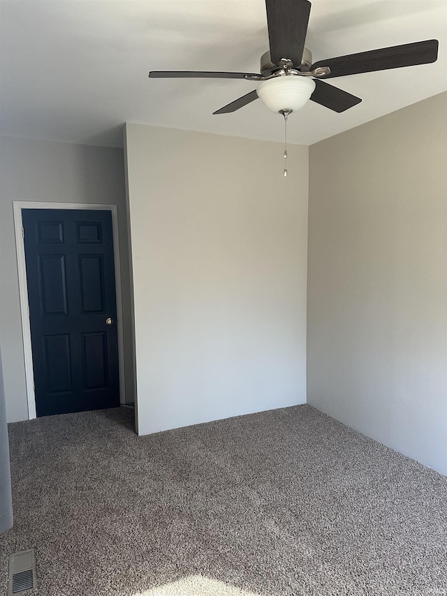 empty room featuring visible vents, carpet, and ceiling fan