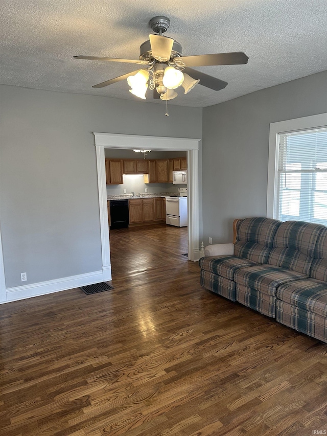 living room featuring baseboards, a textured ceiling, dark wood-type flooring, and ceiling fan