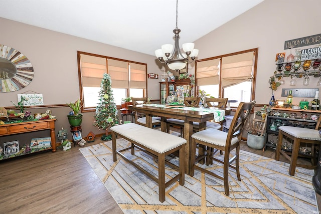 dining area featuring light wood-type flooring, an inviting chandelier, and vaulted ceiling