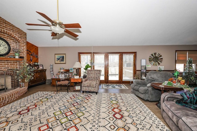 living room featuring a brick fireplace, lofted ceiling, ceiling fan, and wood finished floors