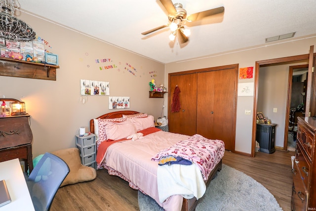 bedroom featuring a closet, visible vents, a ceiling fan, and wood finished floors