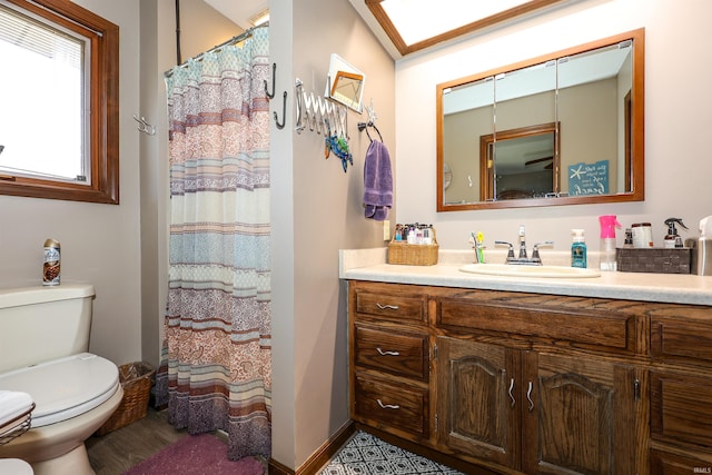 full bath featuring a shower with curtain, toilet, wood finished floors, baseboards, and vanity