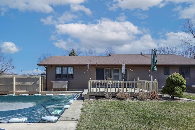 back of property with a fenced in pool, a lawn, a deck, and fence