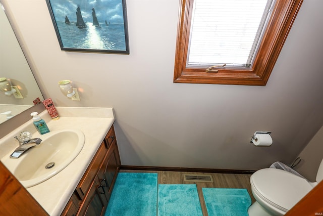 bathroom featuring visible vents, toilet, vanity, and baseboards