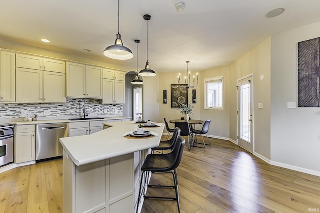 kitchen with a sink, stainless steel appliances, light wood-style floors, and decorative backsplash